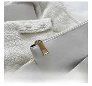 Close-up of golden zipper puller and hexagonal metal studs on white leather bag