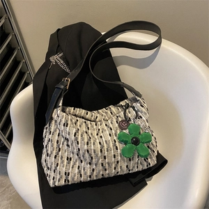 Chic tweed woven tote bag with leather strap and green flower charm on white chair