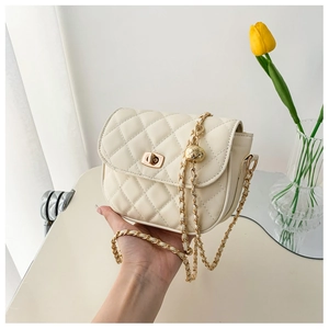 Close-up of beige quilted leather crossbody bag with golden chain and adjustable ball buckle