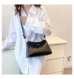 Detail of minimalist black crossbody bag with silver logo and gold hardware accents