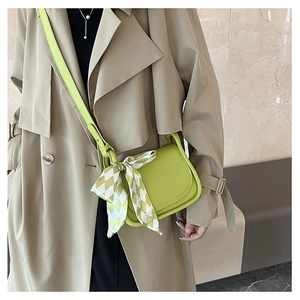 Lime green crossbody bag with checkered silk scarf worn on a trench coat