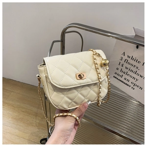 Close-up of beige quilted crossbody bag featuring gold chain strap and metal lock