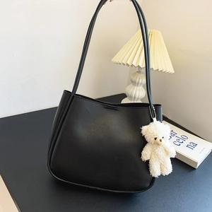 Large capacity black soft leather tote bag with cute plush bear charm on a stylish desk