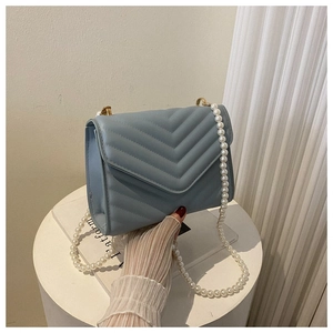 Close-up of light blue quilted crossbody bag featuring elegant pearl chain strap and gold hardware