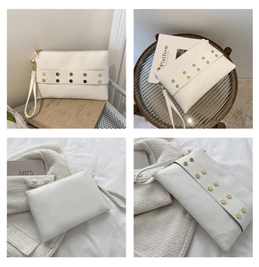 Detail view of white leather envelope clutch with gold hexagonal rivets and wrist strap