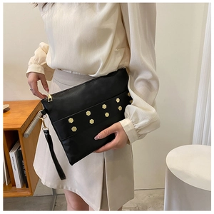 Detail of black leather envelope clutch with gold rivets and wrist strap decoration