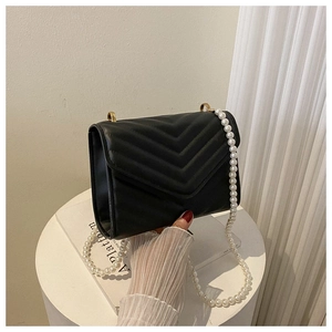 Close-up of V-quilted black leather bag with elegant pearl chain strap and gold hardware