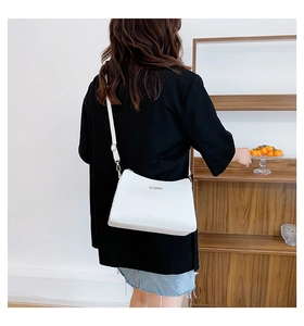 Detail of white minimalist crossbody bag with gold MS. MOODBAG logo and slim strap