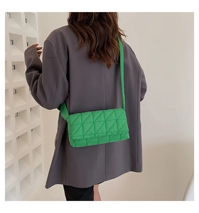 Detail of bright green quilted shoulder bag featuring modern geometric triangle texture