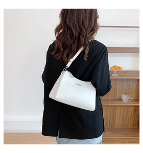 Rear view of model wearing a white crescent shoulder bag with golden brand lettering