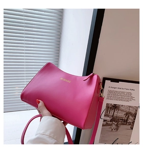 Detail of rose pink trapezoid shoulder bag with gold logo and smooth zipper closure
