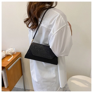 Detail einer schicken schwarzen Glitzer-Baguette-Tasche mit schmalem Riemen am Model