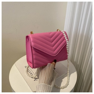 Detailed close-up of hot pink crossbody bag with V-quilted texture and pearl chain handle