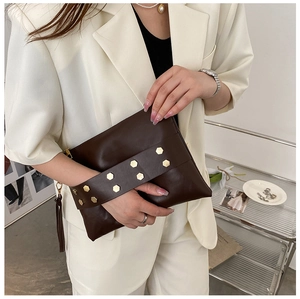 Detail of dark brown leather envelope clutch with gold hexagonal studs and long tassels