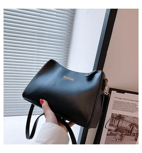 Minimalist black leather shoulder bag detail with gold metal hooks and matte texture