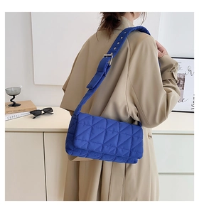 Detailed close-up of a blue quilted shoulder bag with silver buckle and wide strap