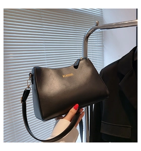 Detail of minimalist black leather shoulder bag with gold branding and zipper closure