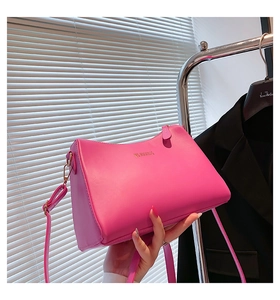Detailed shot of fuchsia crossbody bag with golden logo lettering and sleek shoulder strap