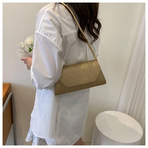 Detail der glitzernden goldenen Handtasche mit schimmernder Textur und schmalem Schultergurt
