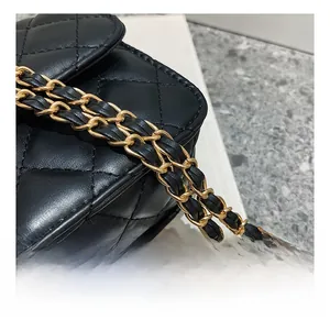Detail of a black quilted leather shoulder bag with a gold metal chain strap