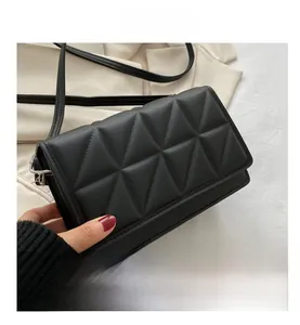 Detail shot of black quilted faux leather crossbody bag with geometric stitching patterns