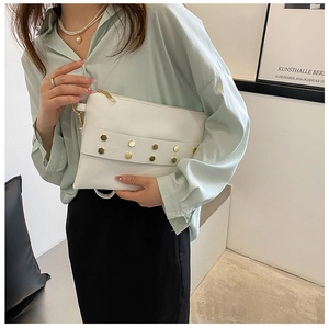 Detailed view of white rivet envelope clutch with gold hexagonal studs and metal zipper