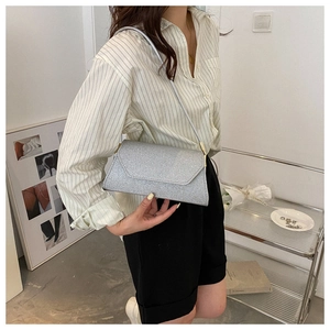 Detail der silbernen Pailletten-Umschlagtasche mit schmalem Riemen in schicker Kulisse