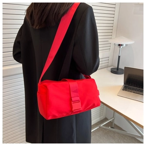 Close-up of bright red nylon crossbody bag with wide strap and matching buckle closure
