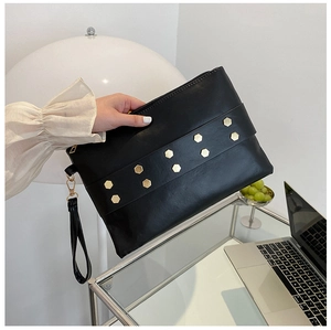 Detail of black leather envelope clutch with gold hexagonal rivets and wrist strap