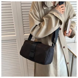 Detail of a black nylon crossbody pillow bag showing the secure buckle and fabric texture