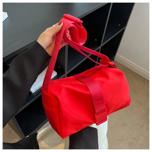 Macro detail of red nylon pillow bag with wide shoulder strap and durable buckle