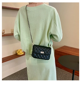 Quilted black chain bag worn over a light green dress showing the rear carry style