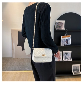 Detailed side view of white quilted crossbody bag with gold chain and turn-lock