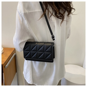 Close-up of black crossbody bag with geometric quilted pattern worn by a model