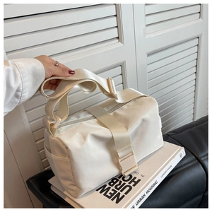 Detail of cream nylon crossbody pillow bag featuring wide strap and plastic buckle