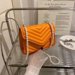 Chic orange V-quilted crossbody bag with elegant faux pearl strap and gold hardware