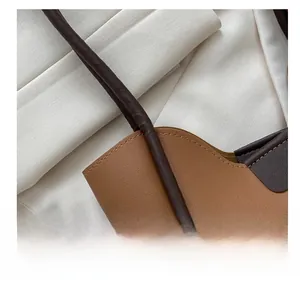 Détail des coutures et du cuir bicolore marron sur la poignée d'un grand sac à main chic