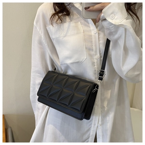 Close-up of black quilted rectangular bag with geometric embossed pattern and shoulder strap