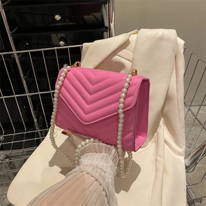 Pink quilted leather crossbody bag with faux pearl strap and V-shaped stitching