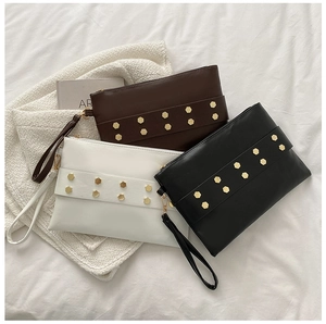 Detailed view of matte leather clutch bags with gold hexagonal studs and wristlets