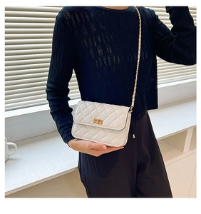Close-up of a white quilted crossbody bag with a gold metal turn-lock and chain strap