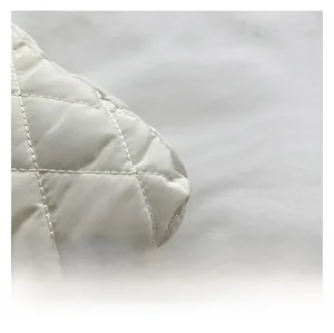 Macro shot of quilted diamond stitch detail on premium cream white crossbody bag fabric