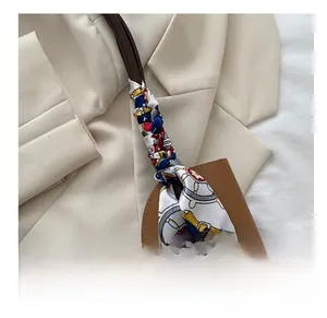 Gros plan sur l'anse d'un sac à main marron ornée d'un foulard en soie coloré