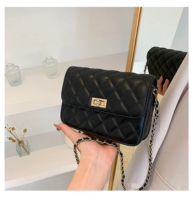 Detailed view of black quilted flap bag with golden metal twist lock and chain strap