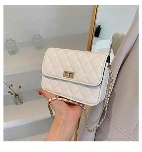 Close-up of quilted cream faux leather crossbody bag featuring a golden twist lock closure