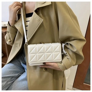 Close-up of white quilted crossbody bag with geometric triangle stitching texture
