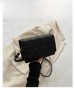Detail of black PU leather crossbody bag with geometric quilted pattern and silver buckle