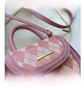 Detail of pink quilted pattern leather bag with gold metal trim and textured stitching