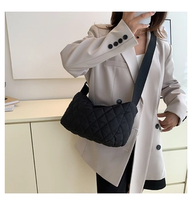 Detail of black quilted crossbody bag with stylish diamond lattice pattern and wide strap
