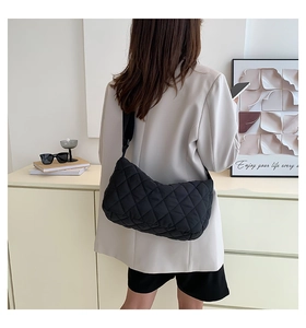 Close-up of black quilted shoulder bag worn by model in minimalist casual setting